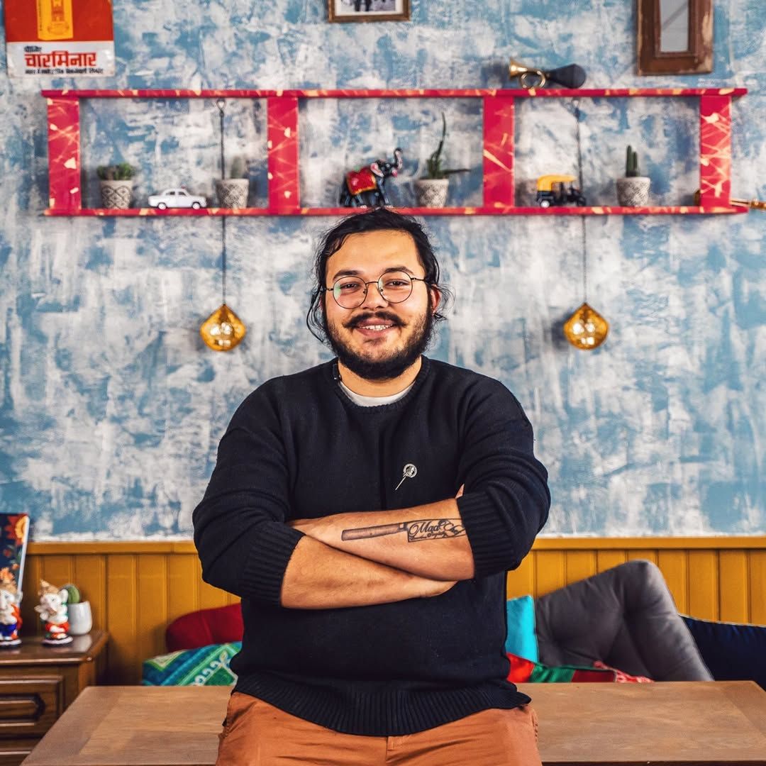 Le Chef Deb au bistro, bras croisés devant le mur d'affiches