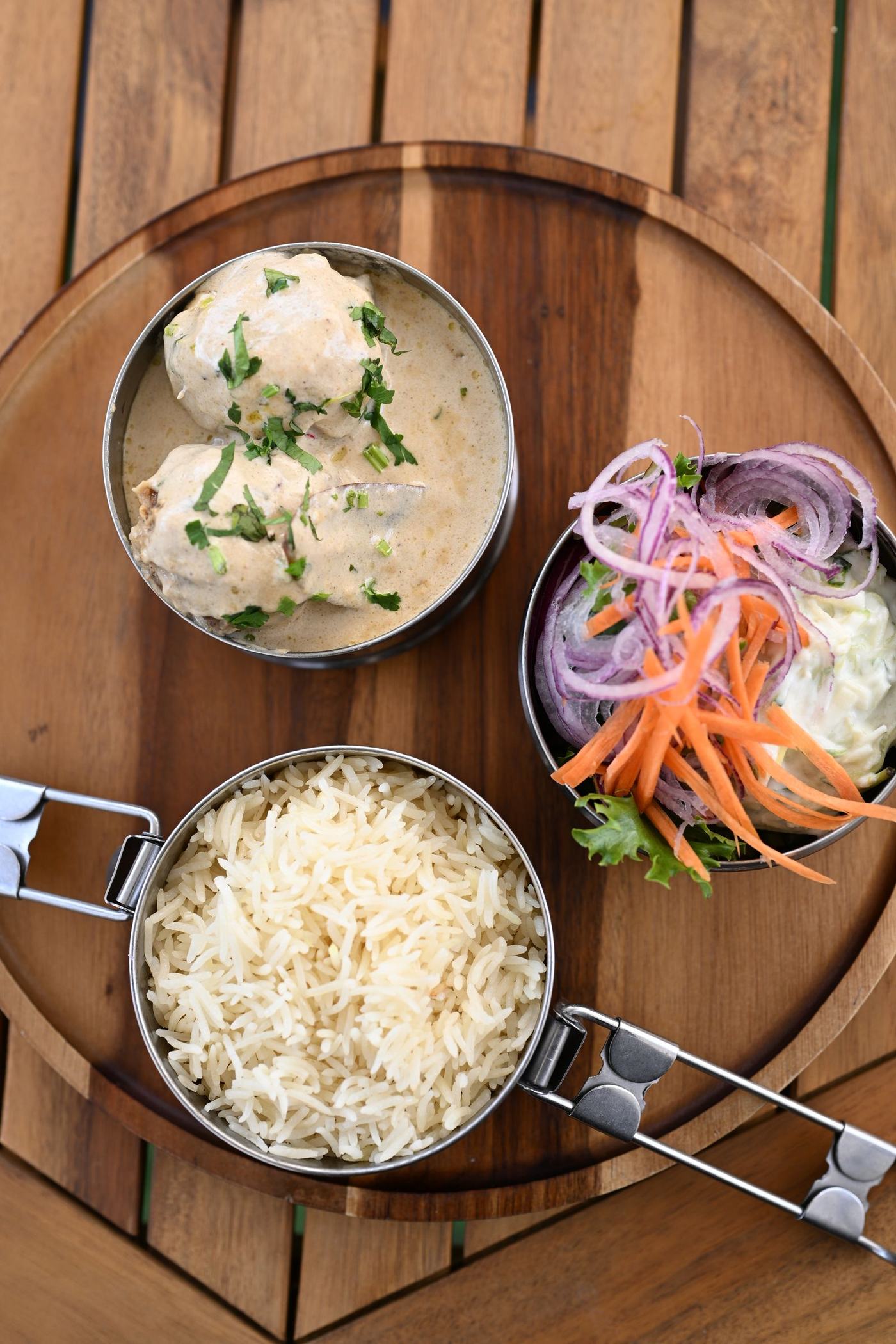 A Deb's Bistro lunch dabba tray with rice, curry, raita and slaw