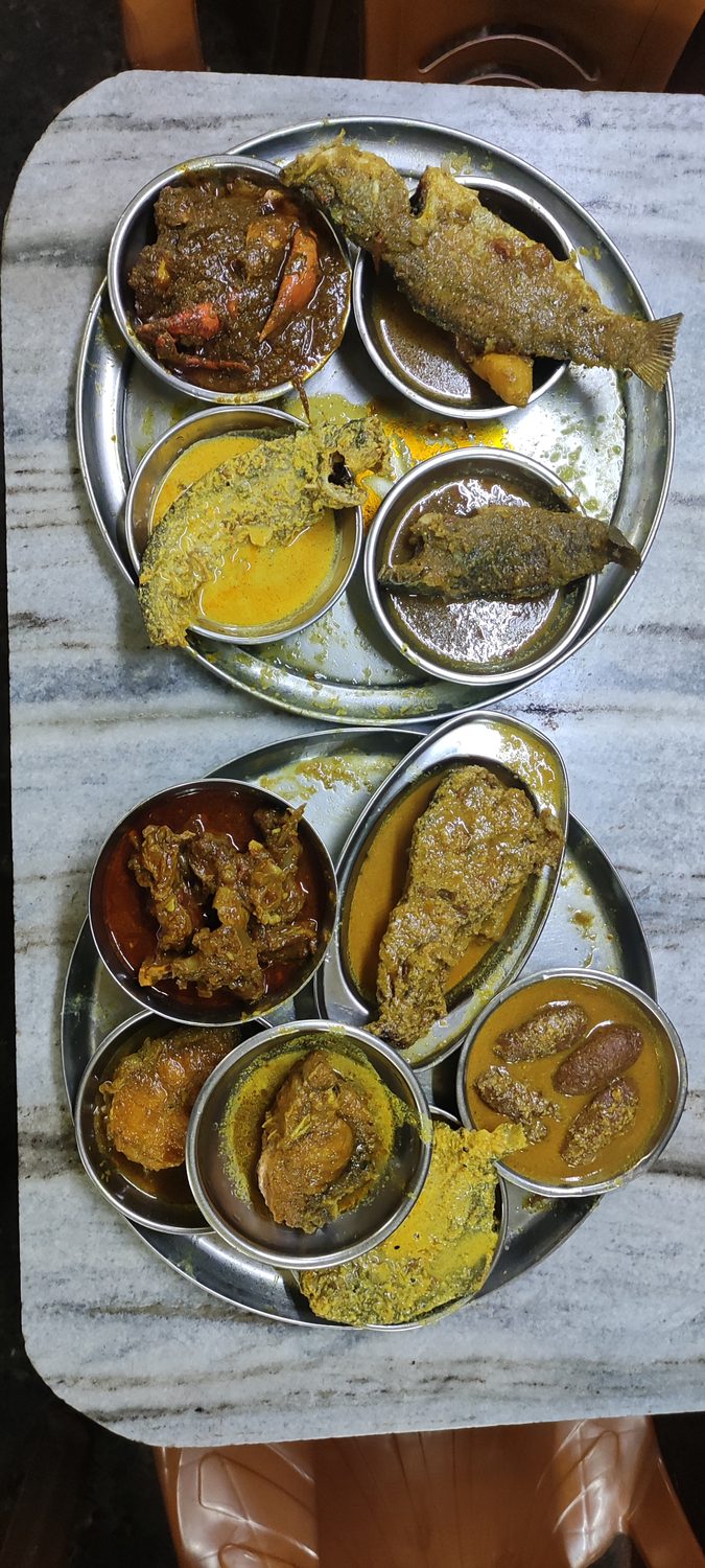Several curries in steel bowls set out on a marble counter